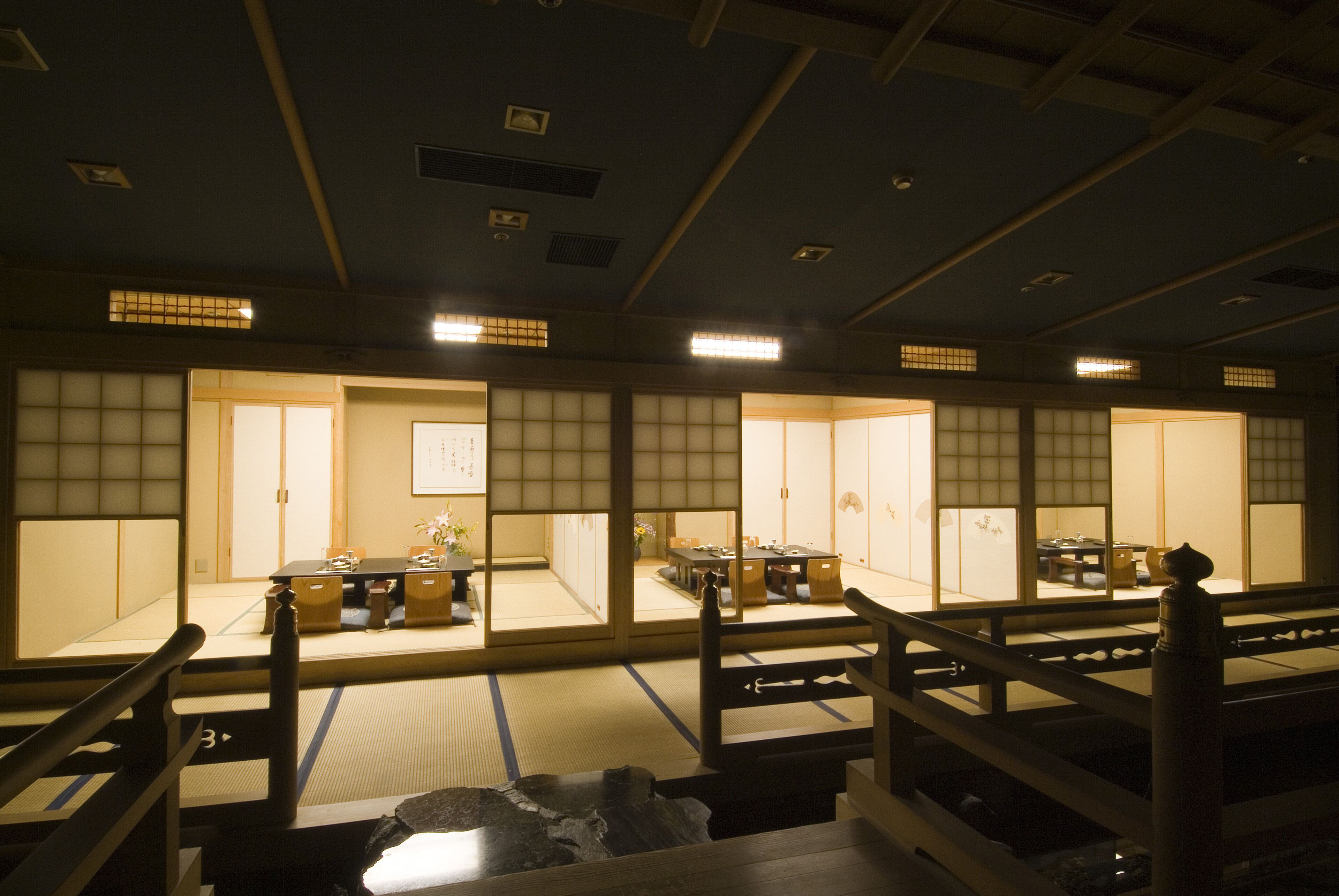 A traditional Japanese room with tatami flooring, sliding doors, and a low wooden table.