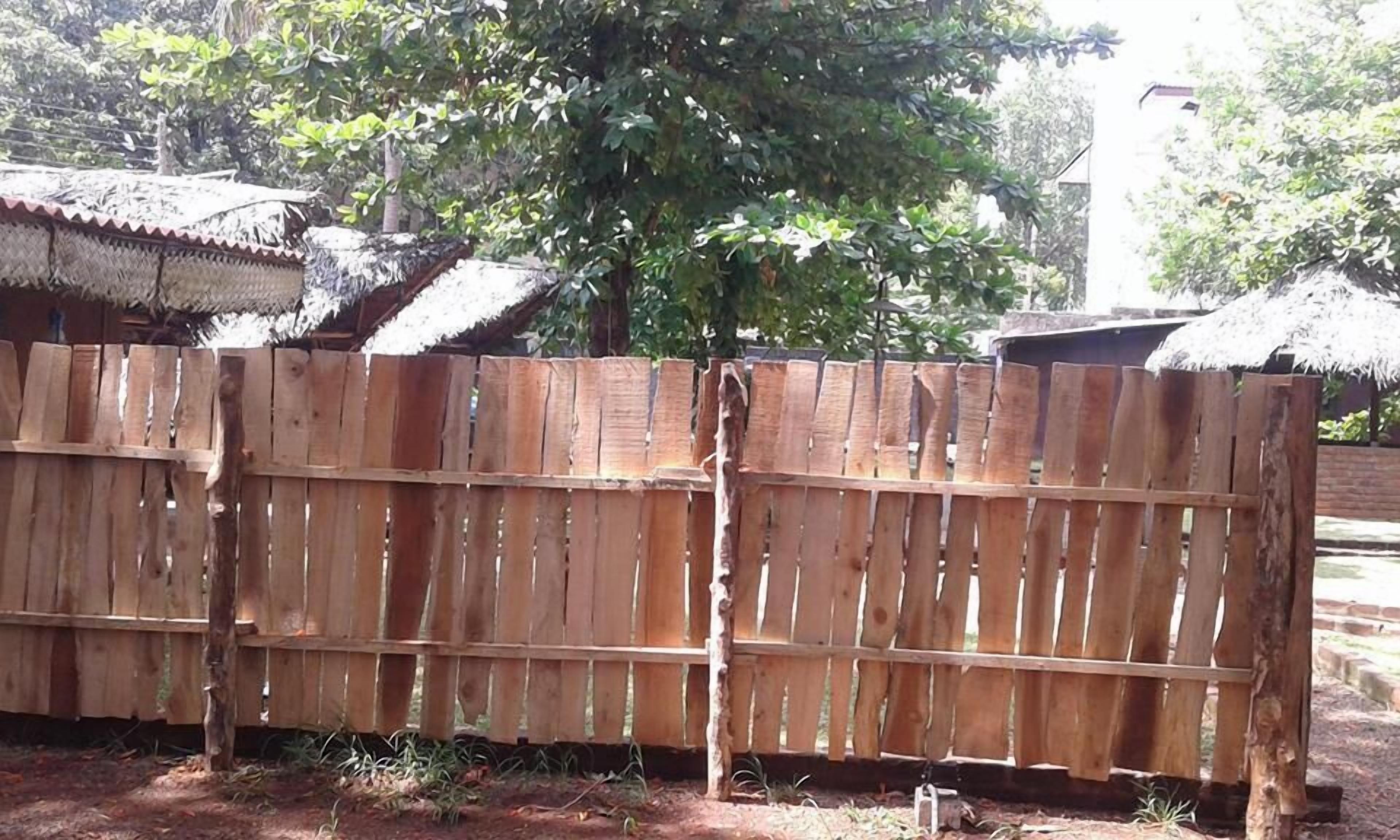 Une clôture en bois avec un arbre en arrière-plan.
