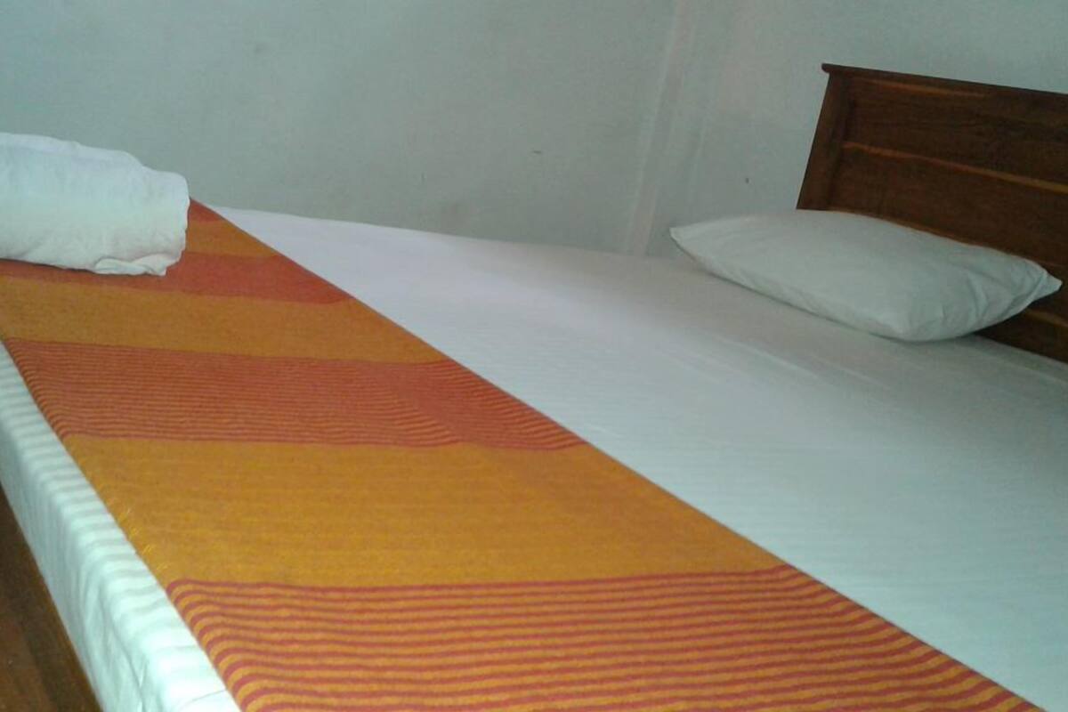 A single bed with a striped blanket, a wooden headboard, and a white pillow.