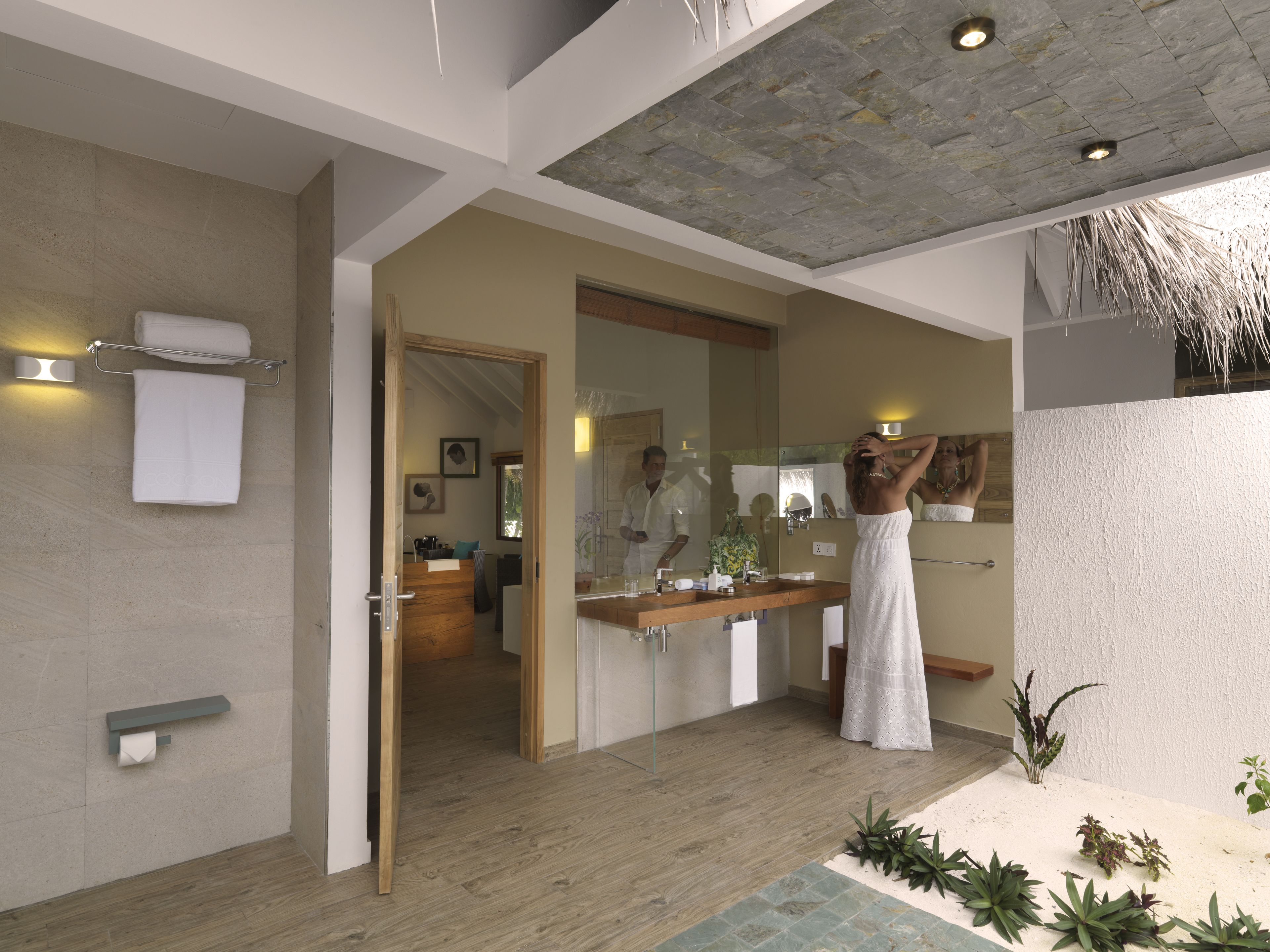 A modern bathroom with a wooden floor, a large mirror, and a sink.