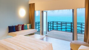 Ein Schlafzimmer mit einem großen Bett, einer Sitzecke und Meerblick vom Balkon.