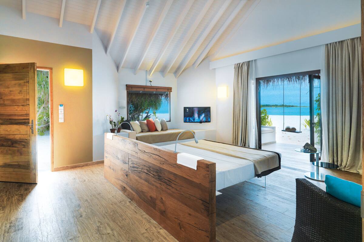 Une chambre moderne avec un lit en bois, une télévision et une vue sur la plage.