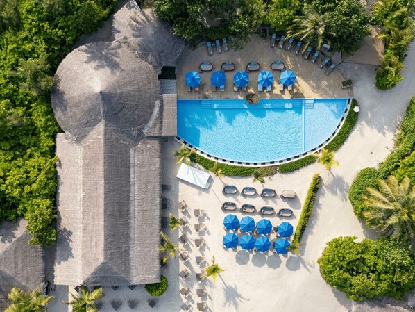 Vista aérea de un complejo turístico con piscina, áreas de descanso y un edificio grande.