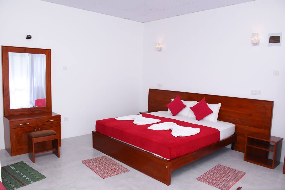 Un dormitorio con cama y mesita de noche de madera, un espejo y un banco.