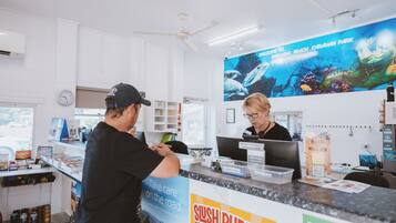 Een receptiebalie met een groot aquarium, een klok en een bordje met de tekst 'Sushi Puppy'.