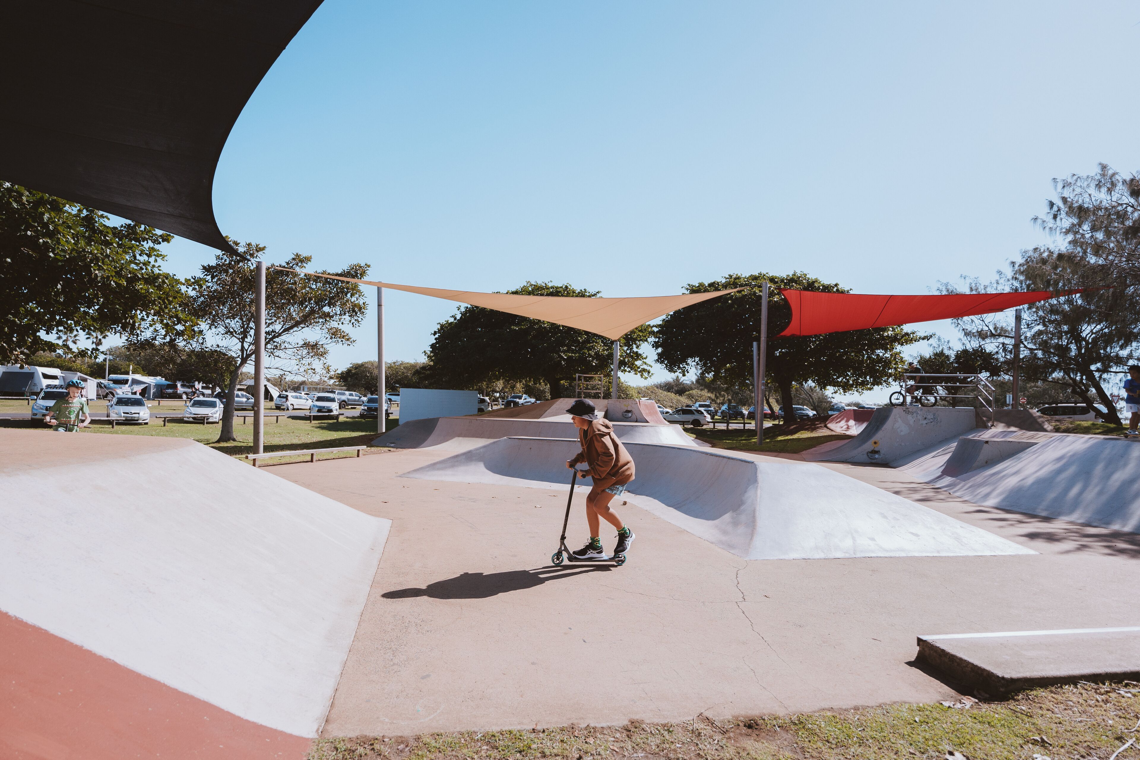 A skate park with ramps and a person riding a scooter.
