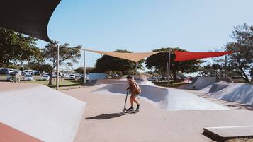 A skate park with ramps and a person riding a scooter.