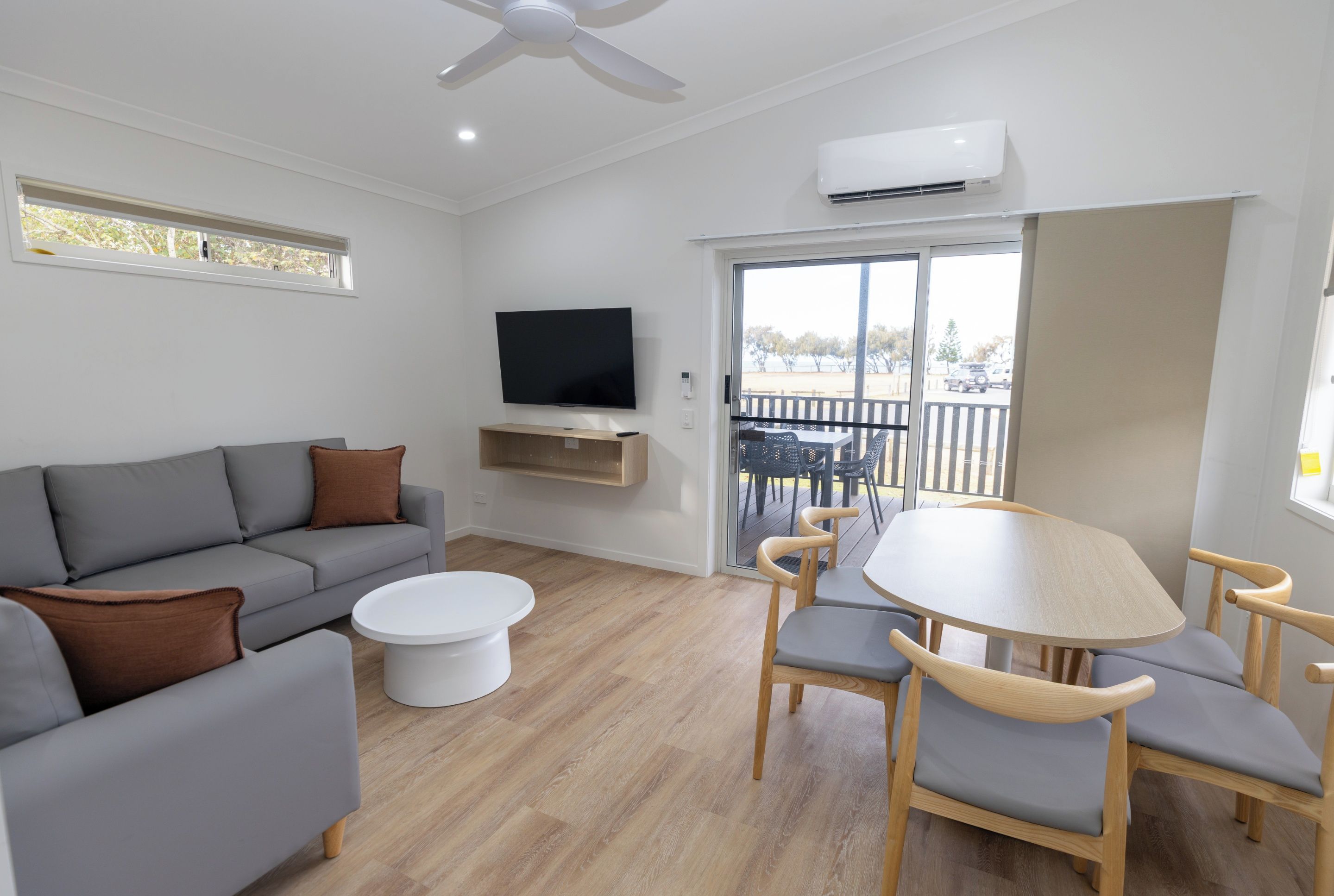 A modern living room with a grey sofa, a white coffee table, and a TV mounted on the wall.