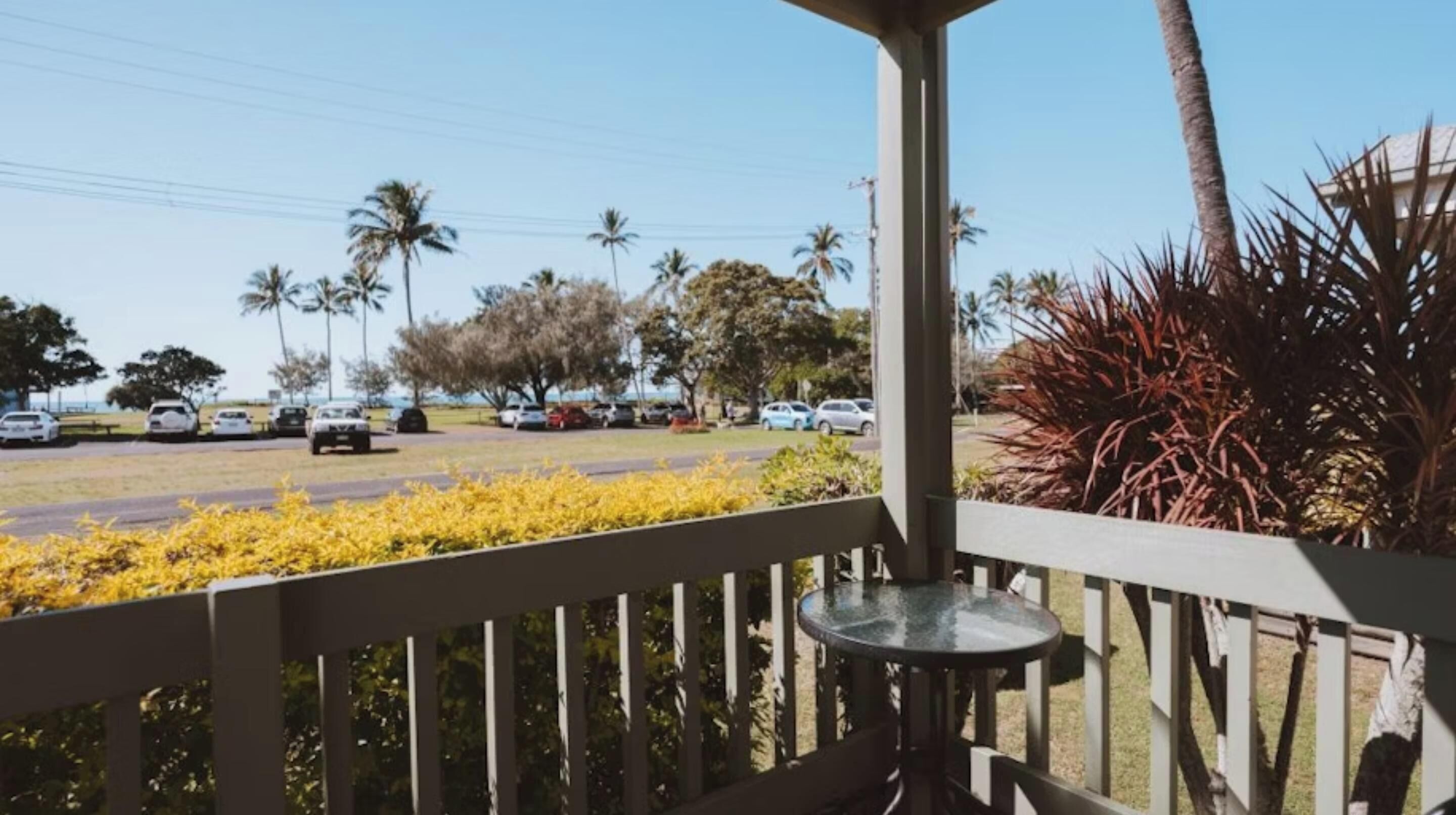 A balcony with a view of a parking lot and palm trees.