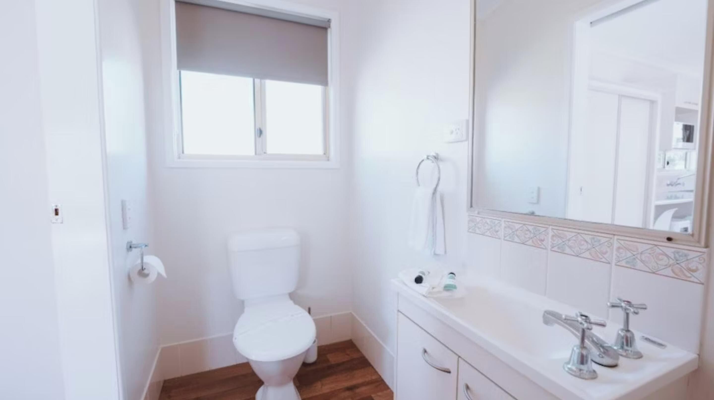 A small, white bathroom with a toilet, a sink, and a mirror.