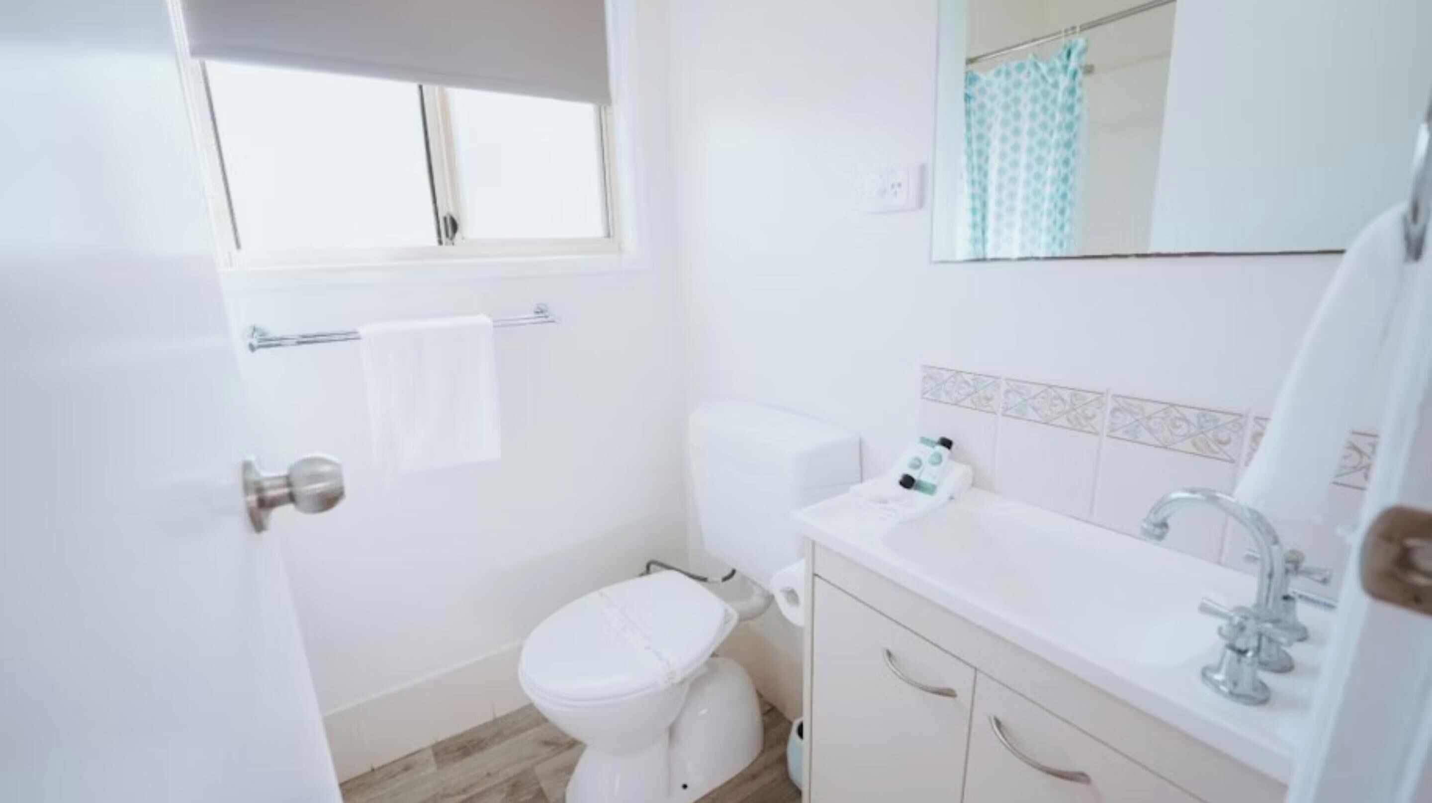 Ein kleines, sauberes Badezimmer mit Toilette, Waschbecken und Spiegel.
