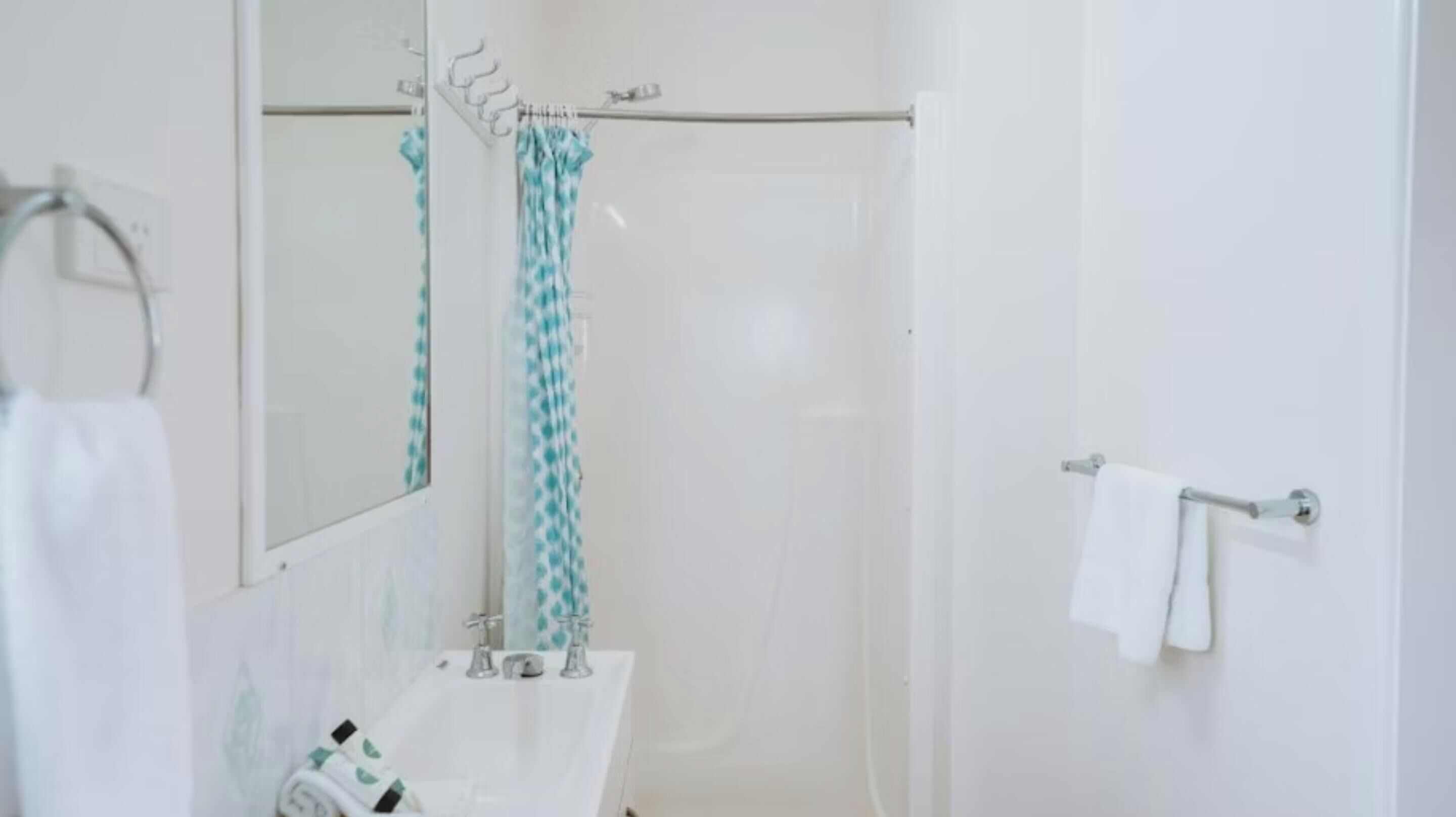 A bathroom with a white sink, a mirror, and a shower area with a glass door.