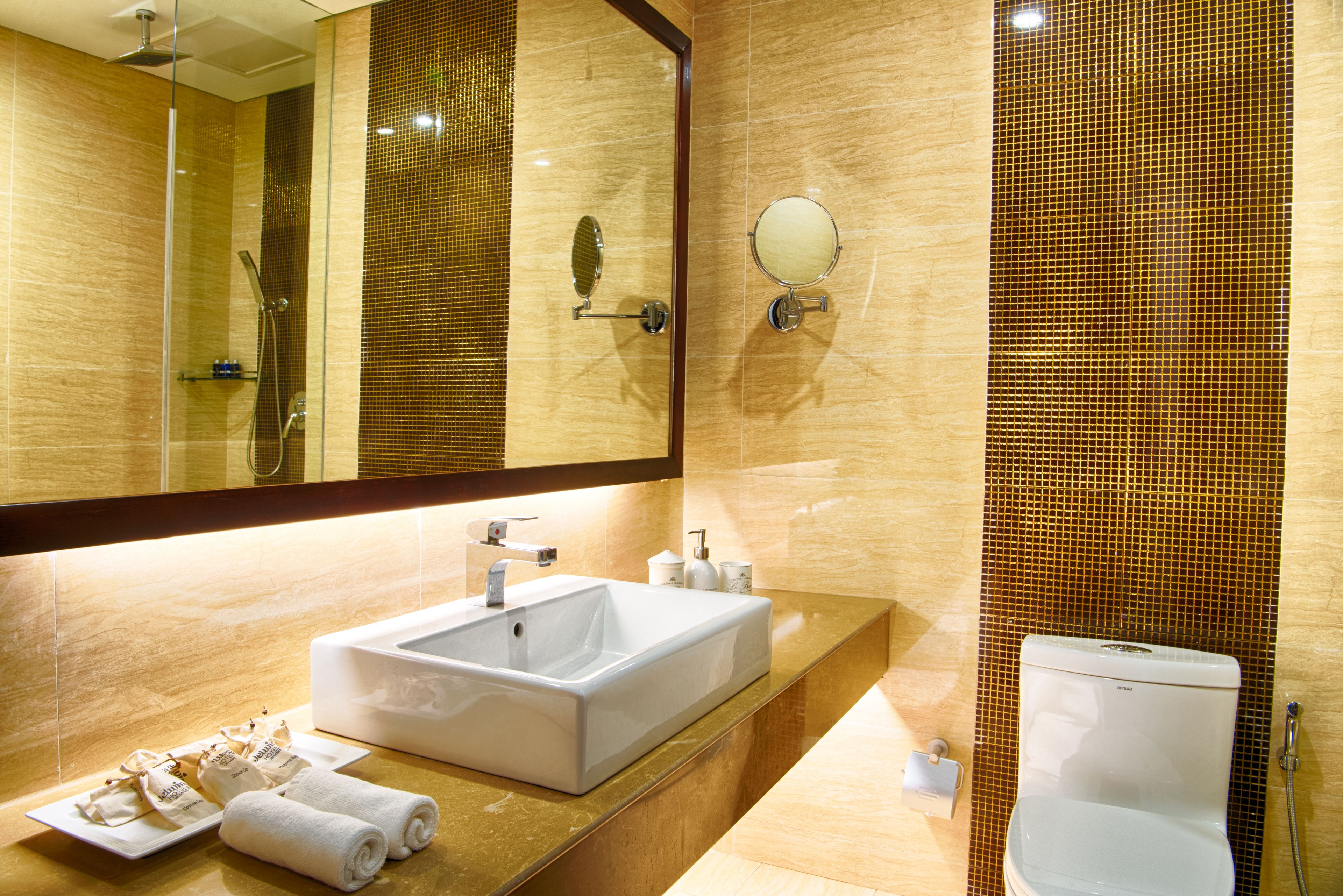 A modern bathroom with a large mirror, a sink, a toilet, and a shower.