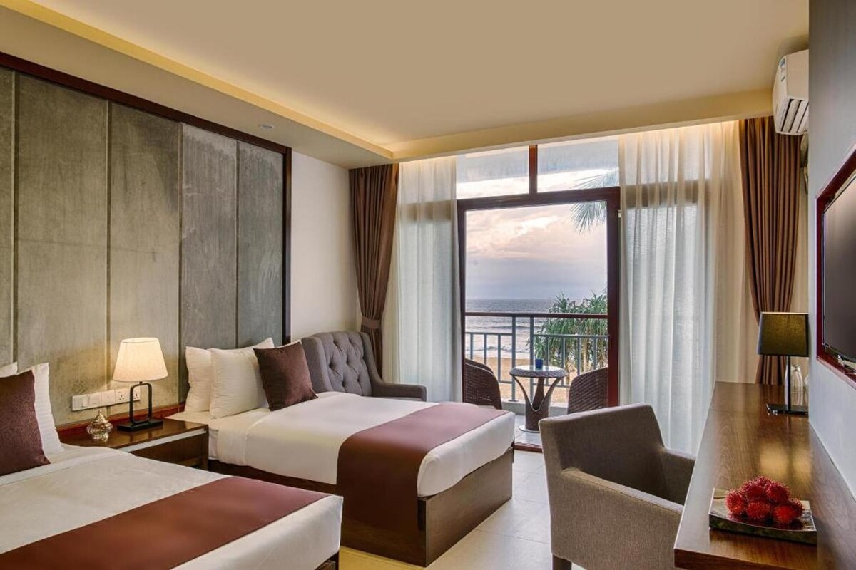 Une chambre d’hôtel avec deux lits, un balcon offrant une vue, un bureau et une télévision.