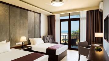 A hotel room with two beds, a desk, a chair, a TV, and a balcony with a view.