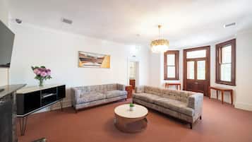 A living room with two grey sofas, a round coffee table, a TV stand, and a painting on the wall.