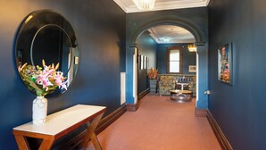 A hallway with a mirror, a vase with flowers, and a bar area in the background. - The Hallows Accommodation (South Bathurst)