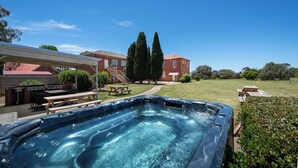 A backyard with a hot tub, picnic tables, and a barbecue area. - The Hallows Accommodation (South Bathurst)