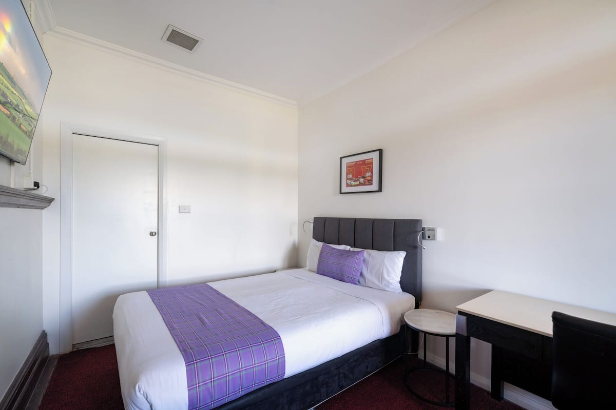 A hotel room with a bed, a small desk, and a chair.