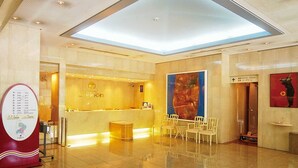 A hotel reception area with a modern design, a reception desk, seating area, and a large artwork on the wall. - Hotel Marix Lagoon (Miyazaki)