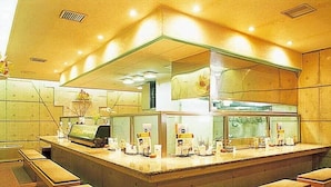 A counter with a cash register, a menu board, and a few chairs. - Hotel Marix Lagoon (Miyazaki)