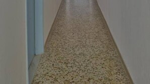 A narrow hallway with a speckled floor, light blue doors, and white walls. - Galaxy Hotel (Andros)
