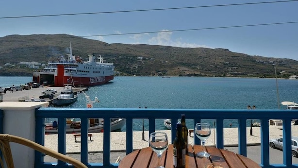 A ferry docked at a harbor with a mountainous backdrop. - Galaxy Hotel (Andros)