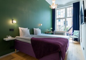 A bedroom with a bed, bedside tables, a window with a view, and a chandelier. - Hellstens Glashus (Stockholm)