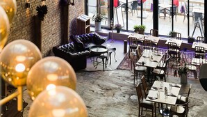 An indoor dining area with brick walls, leather seating, and tables set for dining. - Hellstens Glashus (Stockholm)