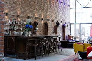 Zona de bar con pared de ladrillo, mostrador de madera y varios taburetes.