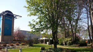 Ein Gebäude mit blauer Fassade und einem Garten mit Bäumen und Rasenfläche.