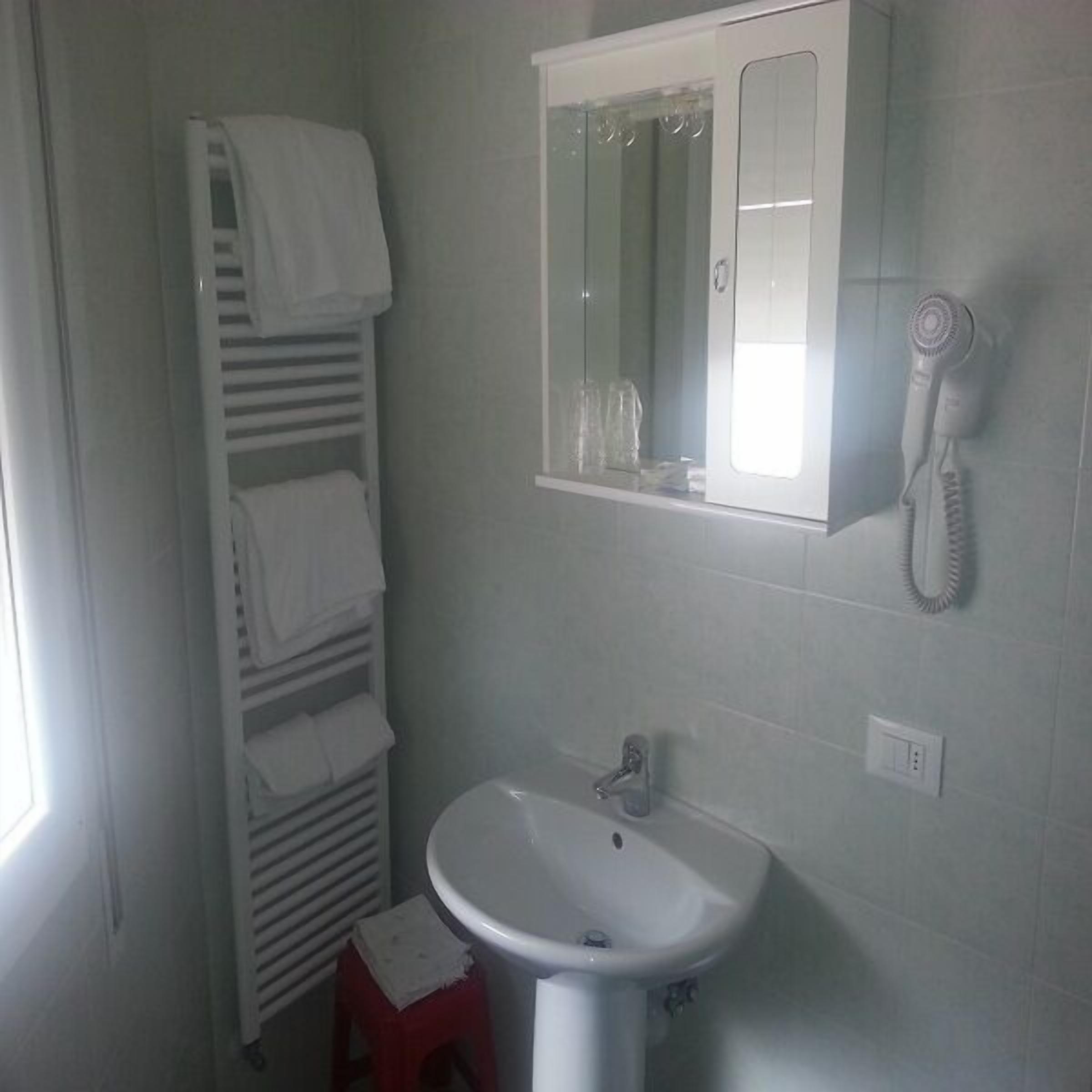 A bathroom with a white sink, a mirror, and a towel rack.