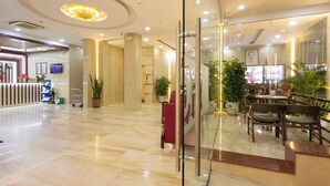 Eine Hotelhalle mit einer Rezeption, einer Sitzecke und einer Treppe zu den oberen Etagen.