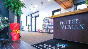 Et hotellets receptionsområde med reception, en rød gavepose og en potteplante.