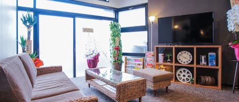 A modern living room with a sofa, wicker chairs, a coffee table, and a TV.