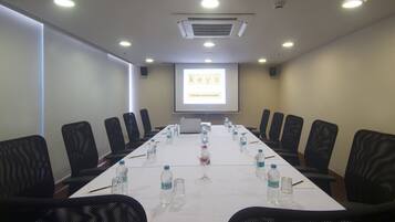 A conference room with a long table, black chairs, water bottles, and a laptop.