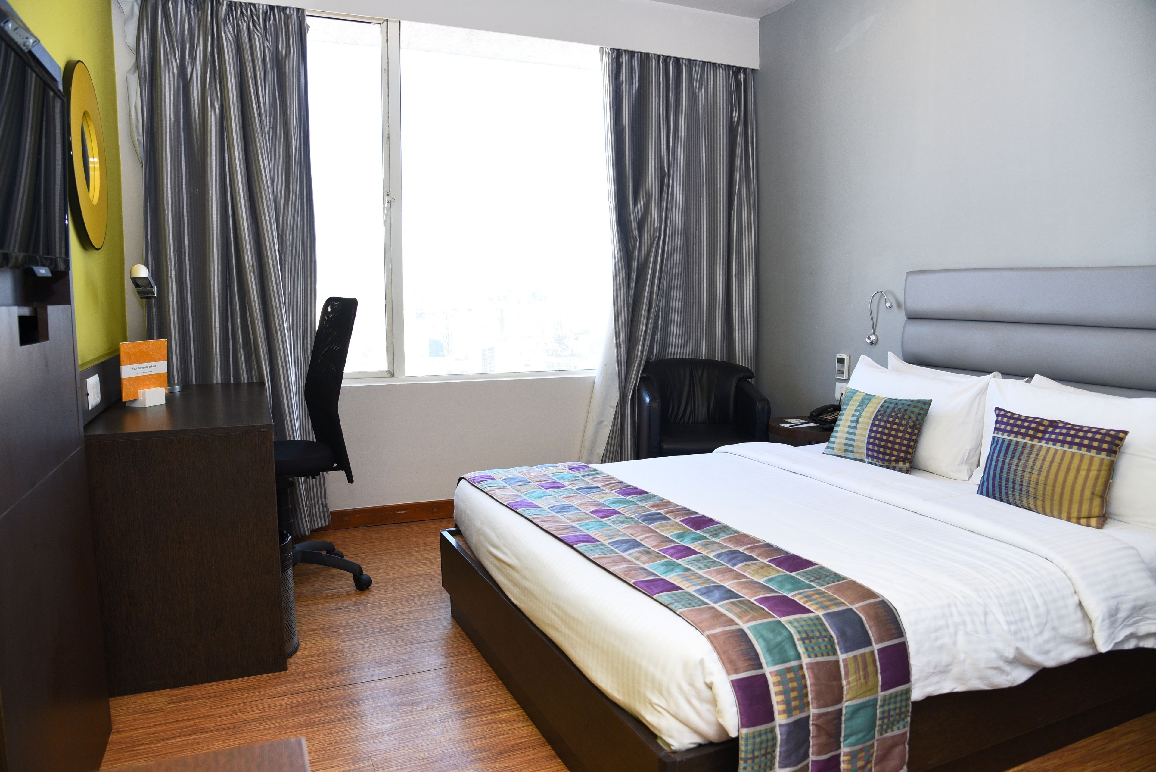A hotel room with a large bed, a desk, and a chair.
