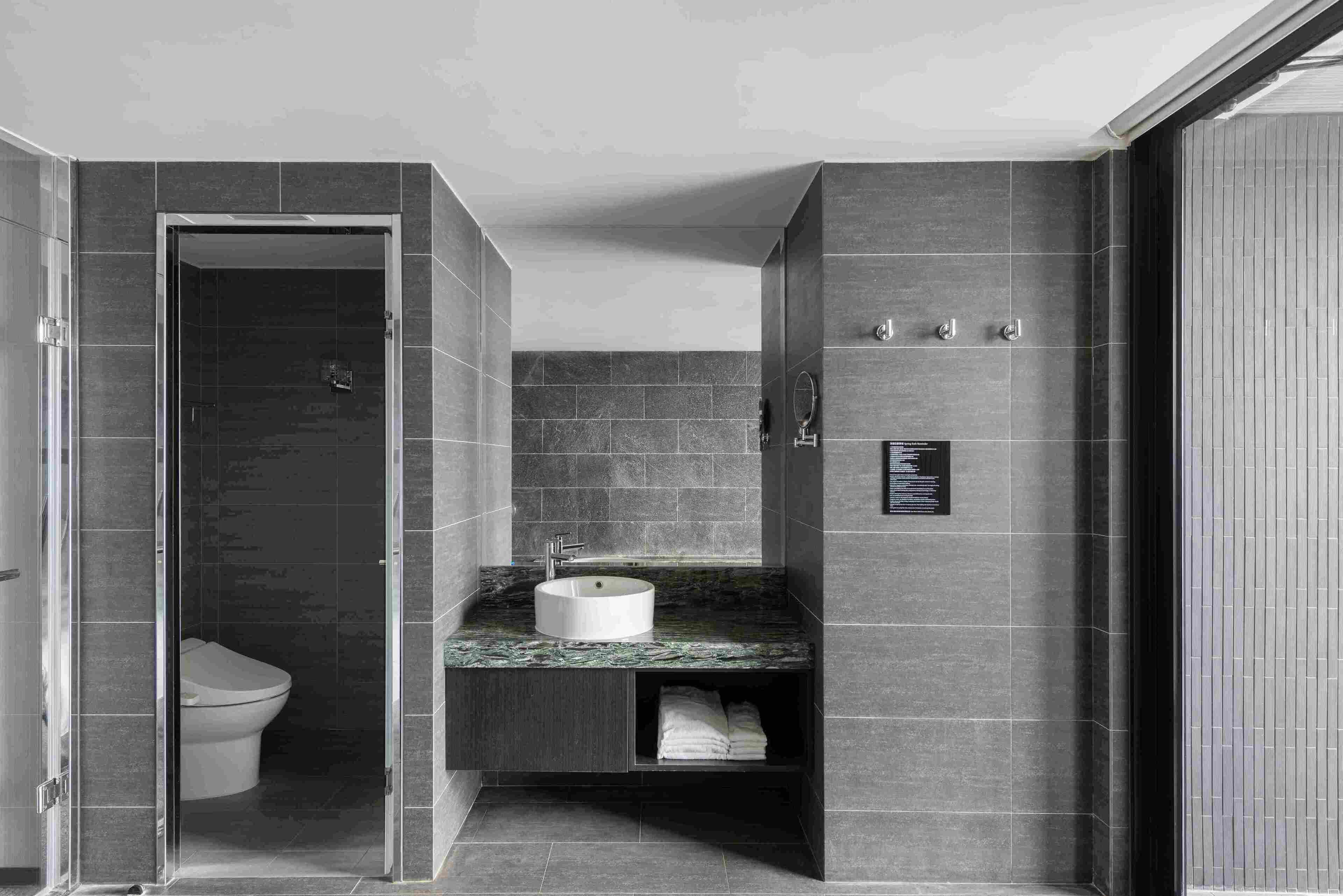 A modern bathroom with a glass-enclosed shower, a white sink, and a built-in toilet.