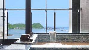 Un baño con un ventanal grande que ofrece vistas a una masa de agua, un lavamanos y un perchero para toallas.