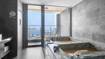 A modern bathroom with a large bathtub, a glass shower enclosure, and a view of the city.