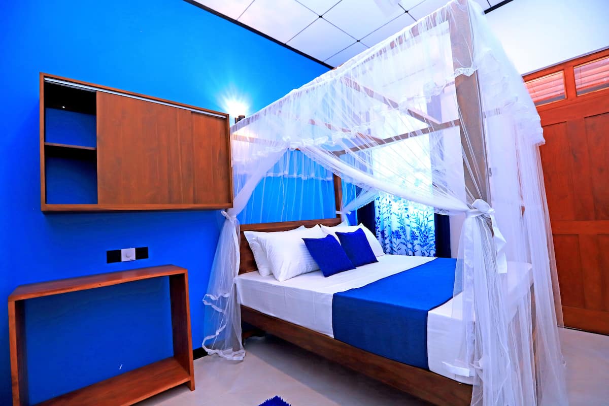 A bedroom with a canopy bed, a bedside table, and a built-in shelf.