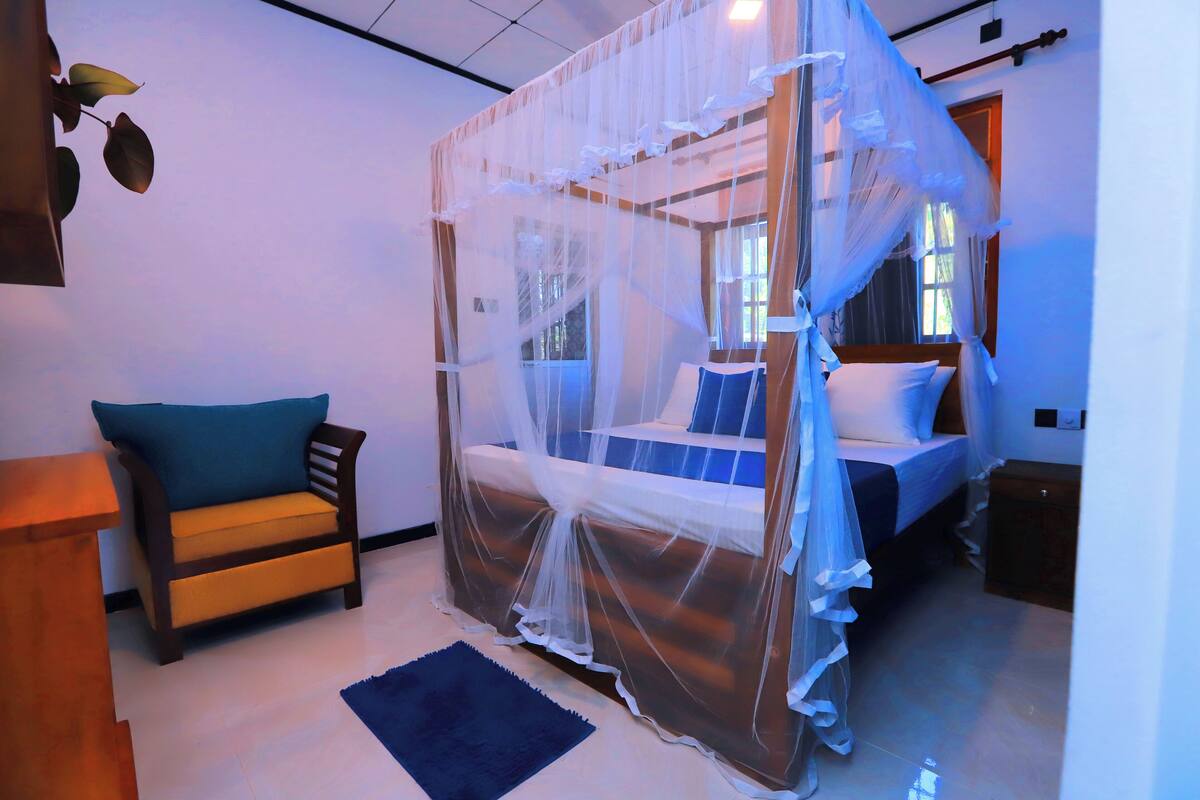 A bedroom with a canopy bed, a sofa, and a small table.