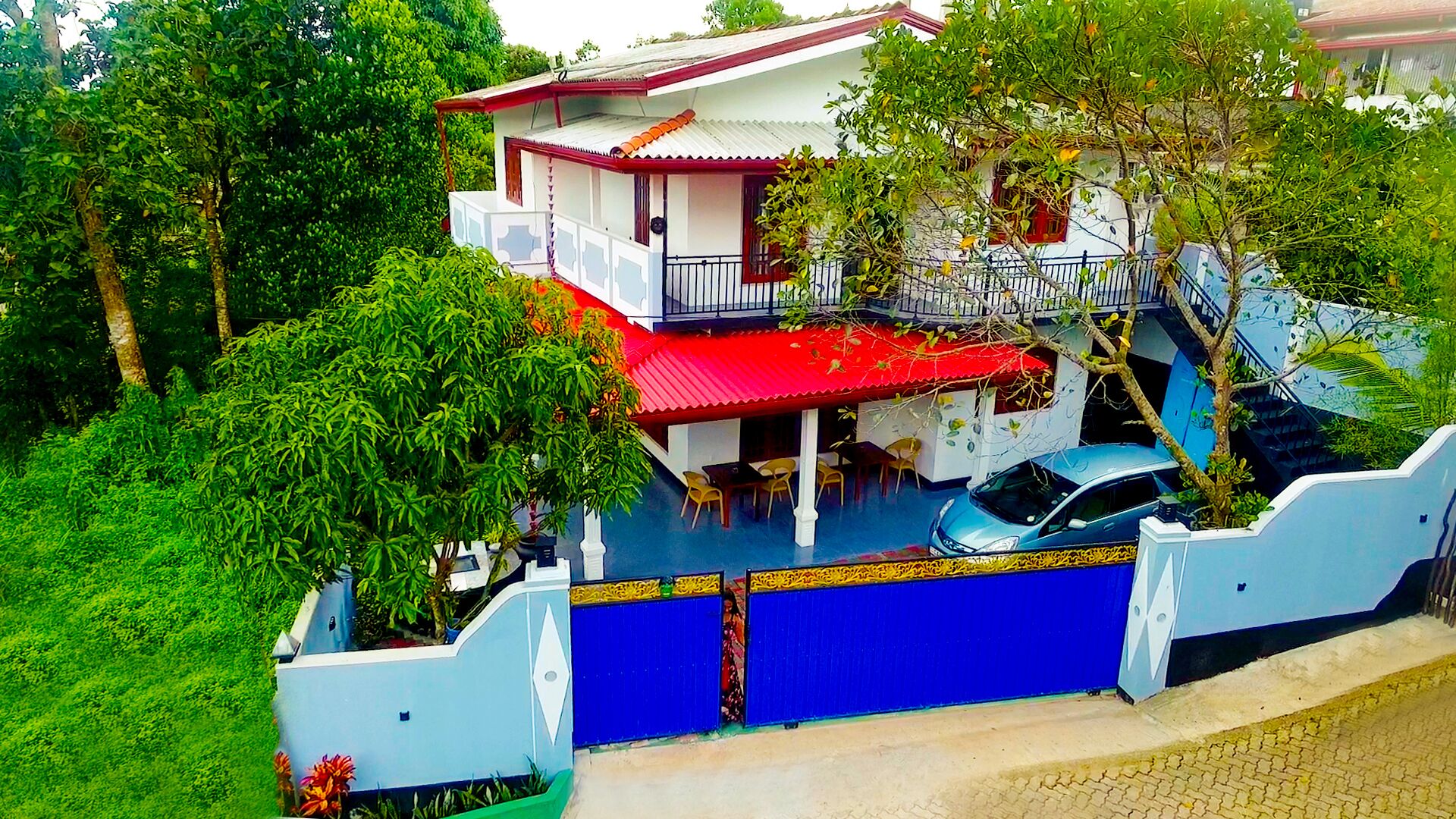 Una casa de dos pisos con techo rojo, un balcón y un portón azul.