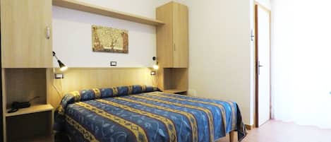 A bedroom with a bed, bedside tables, a wall-mounted lamp, and an air conditioning unit.