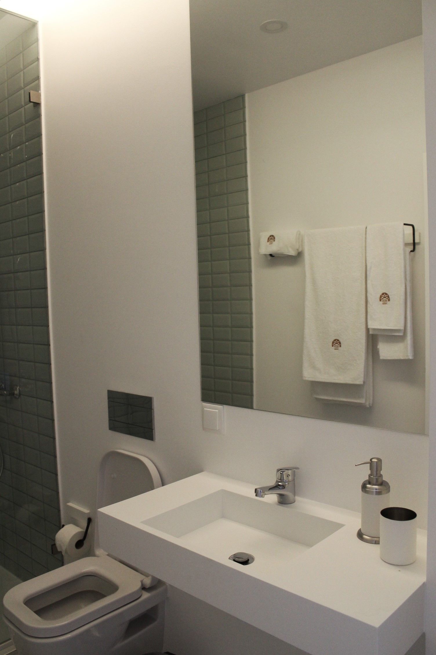 Une salle de bain avec un lavabo blanc, des toilettes, un miroir et un porte-serviettes.