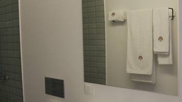 Une salle de bain avec un lavabo blanc, des toilettes, un miroir et un porte-serviettes.