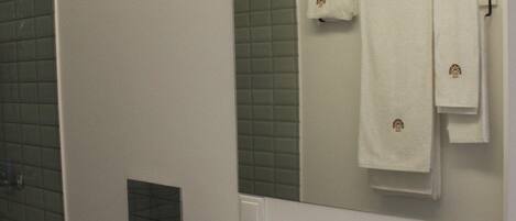 Une salle de bain avec un lavabo blanc, des toilettes, un miroir et un porte-serviettes.