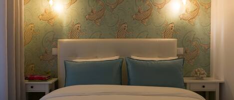 A bedroom with a bed, two bedside tables, and a wall with a fish pattern.
