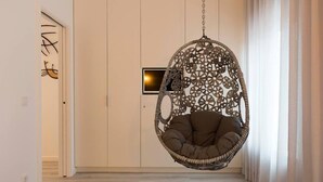 Quarto com cadeira suspensa, cama, guarda-roupa e porta com detalhe decorativo.