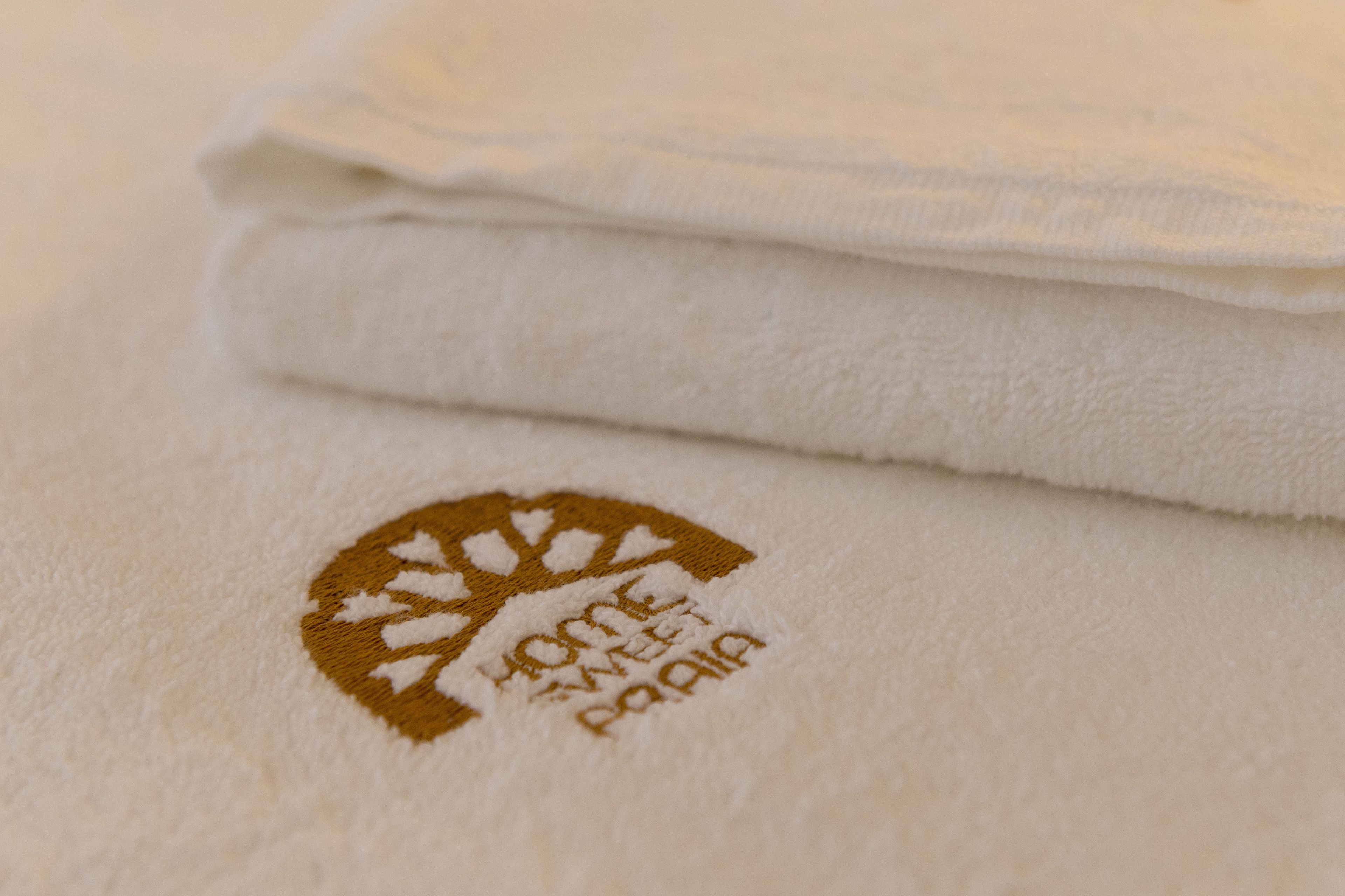 A folded white towel with a logo that reads "HOME SWEET HOME PARIS".